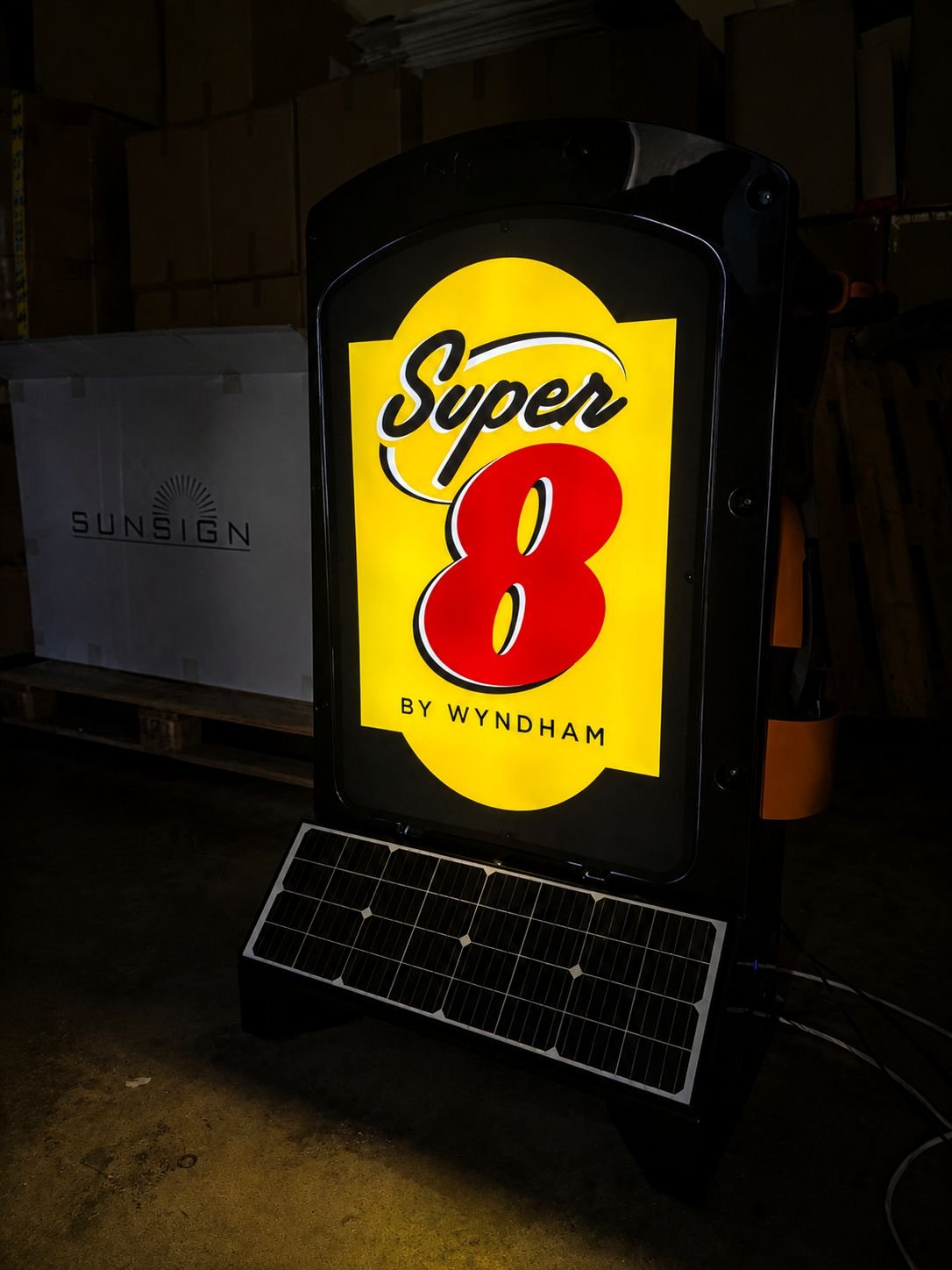 Illuminated hotel brand sign glowing at night in a warehouse